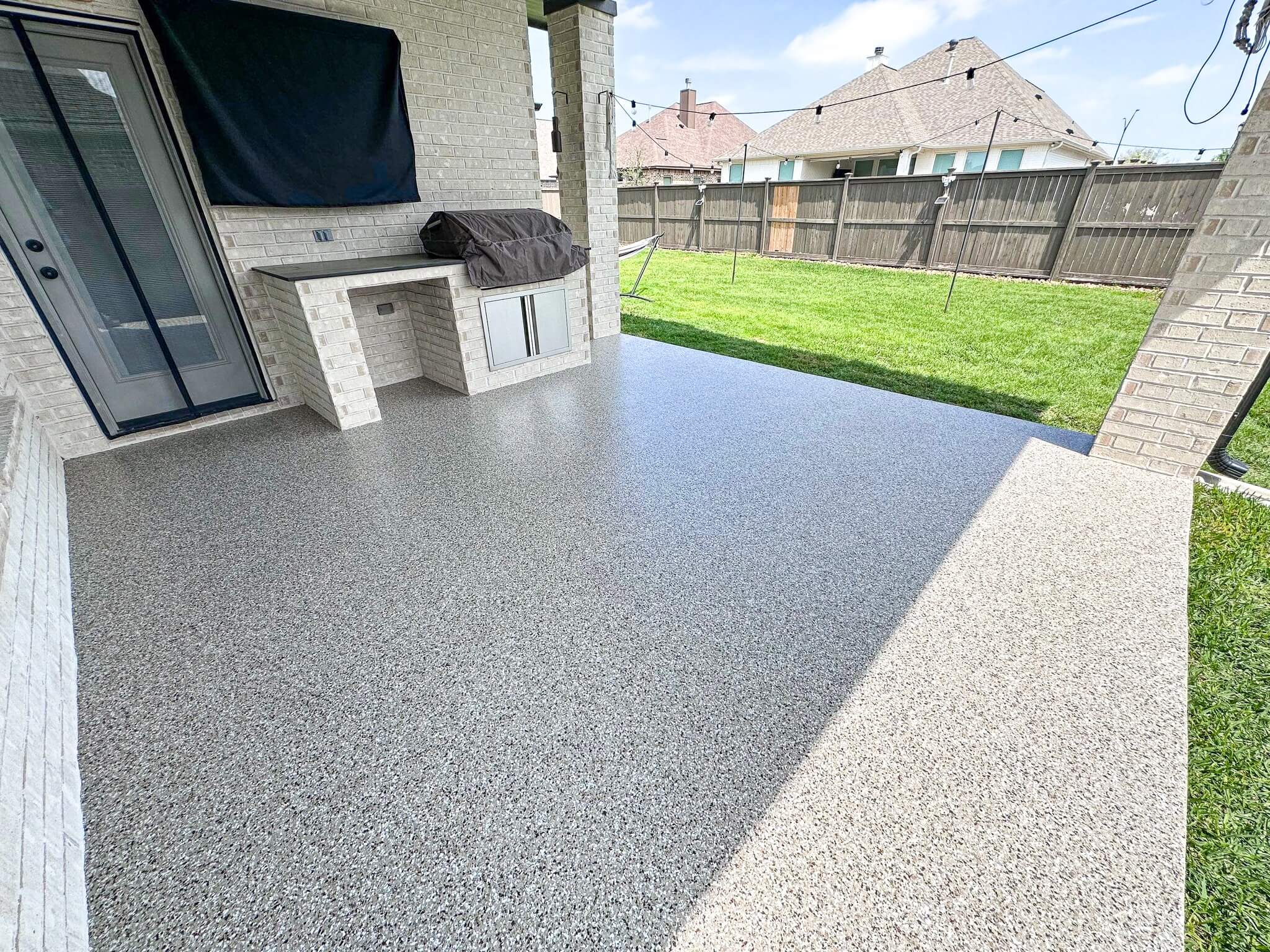 Chip-flake coated outdoor patio with covered kitchen area in a Houston suburb home